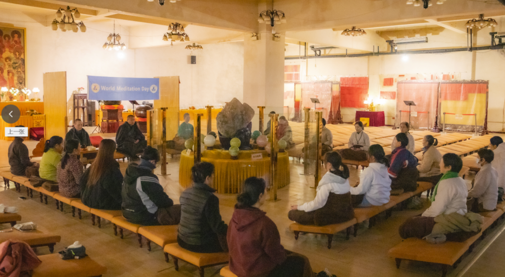 Participants meditate together in a decorated hall.